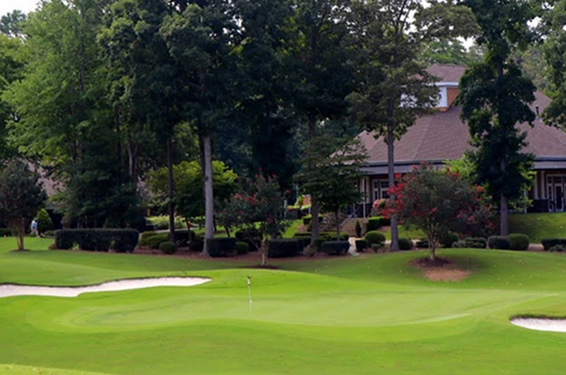 view of golf course with clubhouse in foreground